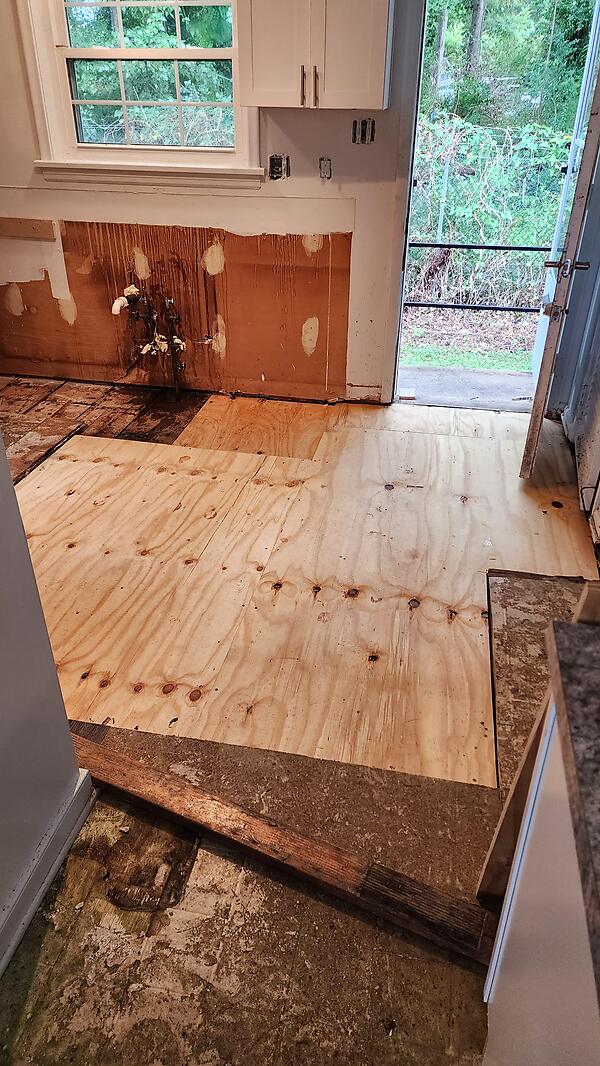New plywood subfloor patch in a kitchen during a carpentry repair